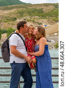 A family of three shares a loving moment by Sulak river during a summer day, with mountains rising in the background and smiles all around, Главрыба, Республика Дагестан, Казбековский район, село Ново-Зубутли. Стоковое фото, фотограф Данила Большаков / Фотобанк Лори