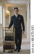Hotel bellboy carrying luggage cart in corridor. Стоковое AI-видео, аниматор Юрий Поздников / Фотобанк Лори