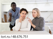 Old woman trying to calm angry middle-aged woman while man quarreling to her. Стоковое фото, фотограф Яков Филимонов / Фотобанк Лори