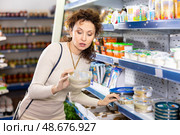 Woman shopper carefully selects salted herring in grocery store. Стоковое фото, фотограф Яков Филимонов / Фотобанк Лори