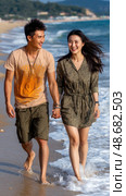 A man and woman are walking on the beach, smiling and holding hands. Стоковое AI-изображение, AI-художник Ярославский Максим / Фотобанк Лори