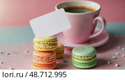 A creative shot of a gift card placed on a stack of colorful macarons, with a cup of coffee in the background. Стоковое AI-видео, аниматор Sergey Grishin / Фотобанк Лори