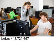 Frustrated teacher talking to neglectful teenage student in computer class. Стоковое фото, фотограф Яков Филимонов / Фотобанк Лори