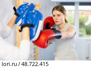 Girls works out strength and speed of boxing punch mitts with help of partner in boxing paws. Стоковое фото, фотограф Яков Филимонов / Фотобанк Лори