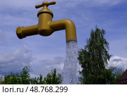 Большой исскуственный водяной кран со льющейся водой на фоне неба. Редакционное фото, фотограф Виталий Шкапский / Фотобанк Лори