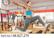 Girl performs exercise on reformer to improve coordination, balance, and posture. Стоковое фото, фотограф Яков Филимонов / Фотобанк Лори