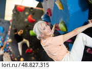 Mature female fitness climber training at bouldering gym.Woman rise up on artificial climbing wall. Стоковое фото, фотограф Яков Филимонов / Фотобанк Лори