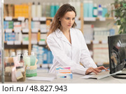Woman employee in labcoat works in pharmacy using computer. Стоковое фото, фотограф Яков Филимонов / Фотобанк Лори