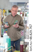 Elderly man holds several toothbrushes, carefully choosing them for his family. European buys dental hygiene products. Стоковое видео, видеограф Яков Филимонов / Фотобанк Лори