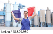 Smiling young woman worker posing with France flag in hands against background of factory. Стоковое видео, видеограф Яков Филимонов / Фотобанк Лори