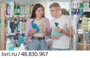 Positive young couple choosing convenient cleaning spray in household goods shop. Стоковое видео, видеограф Яков Филимонов / Фотобанк Лори