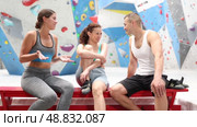 Three friends, man and woman, discuss their climbs on climbing wall without safety net, sitting on bench in a recreation area. Стоковое видео, видеограф Яков Филимонов / Фотобанк Лори