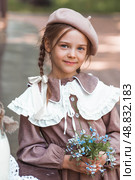 Vintage women's accessories and retro-style clothing. A small, beautiful girl with bows in her hair, in a beige dress and a beret outdoors. Стоковое фото, фотограф Photojuli / Фотобанк Лори