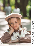 Vintage women's accessories and retro-style clothing. A small, beautiful girl with bows in her hair, in a beige dress and a beret outdoors. Стоковое фото, фотограф Photojuli / Фотобанк Лори