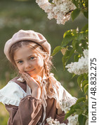 Vintage women's accessories and retro-style clothing. A small, beautiful girl with bows in her hair, in a beige dress and a beret outdoors. Стоковое фото, фотограф Photojuli / Фотобанк Лори