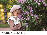 Vintage women's accessories and retro-style clothing. A small, beautiful girl with bows in her hair, in a beige dress and a beret outdoors. Стоковое фото, фотограф Photojuli / Фотобанк Лори