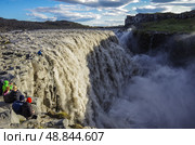 Турист на краю водопада Деттифосс (Detifoss ). Одна из лучших достопримечательностей Исландии. Деттифосс - самый мощный водопад в Исландии и во всей Европе (2014 год). Стоковое фото, фотограф Дымов Игорь / Фотобанк Лори