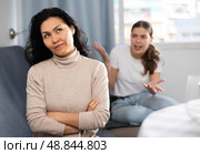 Upset woman sitting at home while girl calming her, asking to forgive after argument. Стоковое фото, фотограф Яков Филимонов / Фотобанк Лори