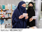 Two Muslim women choosing pills in box in drugstore. Стоковое фото, фотограф Яков Филимонов / Фотобанк Лори