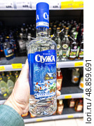 Бутылка русской водки «Стужа» в руке мужчины. Различные бутилированные алкогольные напитки и крепкие напитки. Редакционное фото, фотограф FotograFF / Фотобанк Лори