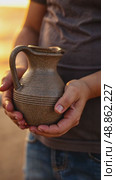 A child's small hands holding a clay water jug, symbolizing the thirst of Imam Hussain family, under the fading light of sunset. Стоковое AI-видео, аниматор Sergey Grishin / Фотобанк Лори