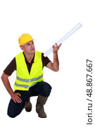Tradesman holding up a rolled-up blueprint. Стоковое фото, агентство Ingram Publishing / Фотобанк Лори
