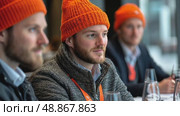Three men in vibrant orange beanies participate in a collaborative workshop while seated at a well-lit table, fostering innovation and ideas. Стоковое AI-видео, аниматор Данила Большаков / Фотобанк Лори