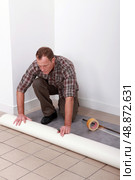 Man unrolling carpet roll. Стоковое фото, агентство Ingram Publishing / Фотобанк Лори