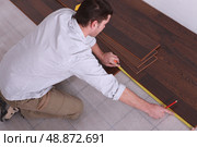 Man measuring wooden flooring. Стоковое фото, агентство Ingram Publishing / Фотобанк Лори