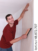 Decorator smoothing wallpaper. Стоковое фото, агентство Ingram Publishing / Фотобанк Лори
