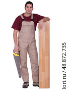 Man stood with laminate flooring and saw. Стоковое фото, агентство Ingram Publishing / Фотобанк Лори