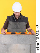 Construction worker measuring an angle with a spirit level. Стоковое фото, агентство Ingram Publishing / Фотобанк Лори