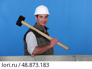 Tradesman holding a mallet and standing behind a low wall. Стоковое фото, агентство Ingram Publishing / Фотобанк Лори