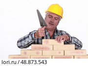 Mason tapping brick into place. Стоковое фото, агентство Ingram Publishing / Фотобанк Лори