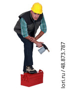 Tradesman posing with his foot propped on a toolbox and holding a spray gun. Стоковое фото, агентство Ingram Publishing / Фотобанк Лори