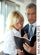 mature businessman consulting his agenda with blonde secretary by his side. Стоковое фото, агентство Ingram Publishing / Фотобанк Лори