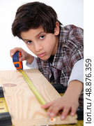 Young boy measuring a plank of wood. Стоковое фото, агентство Ingram Publishing / Фотобанк Лори