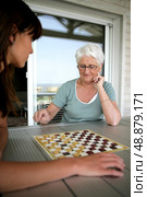 Young woman and senior woman playing checkers. Стоковое фото, агентство Ingram Publishing / Фотобанк Лори
