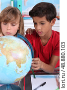 two children looking a globe in a classroom. Стоковое фото, агентство Ingram Publishing / Фотобанк Лори