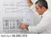 Architect examining a blueprint in detail. Стоковое фото, агентство Ingram Publishing / Фотобанк Лори