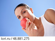 Brunette biting into red apple. Стоковое фото, агентство Ingram Publishing / Фотобанк Лори