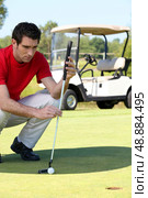 Golfer crouched next to the hole. Стоковое фото, агентство Ingram Publishing / Фотобанк Лори