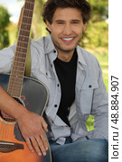 Man sitting in park with guitar. Стоковое фото, агентство Ingram Publishing / Фотобанк Лори