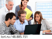 Informal team of people sitting round a laptop computer. Стоковое фото, агентство Ingram Publishing / Фотобанк Лори