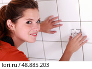 Woman fitting an electrical outlet in bathroom. Стоковое фото, агентство Ingram Publishing / Фотобанк Лори