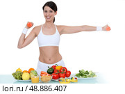 Woman in gym-wear stood with vegetables. Стоковое фото, агентство Ingram Publishing / Фотобанк Лори