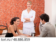 a couple dining at a restaurant and a waitress crossing her arms. Стоковое фото, агентство Ingram Publishing / Фотобанк Лори