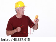 Tradesman looking at his multimeter’s display. Стоковое фото, агентство Ingram Publishing / Фотобанк Лори