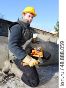 Mason kneeling by wall with lump hammer. Стоковое фото, агентство Ingram Publishing / Фотобанк Лори