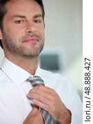 Man rearranging his tie. Стоковое фото, агентство Ingram Publishing / Фотобанк Лори